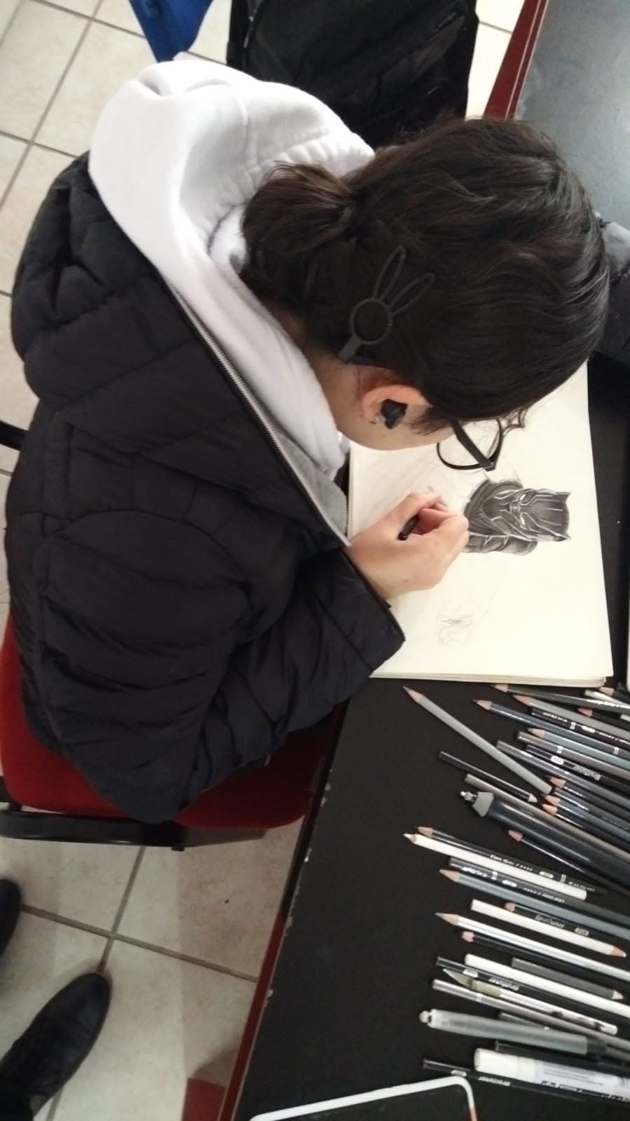 Alumna dibujando con lápices en taller de artes plásticas